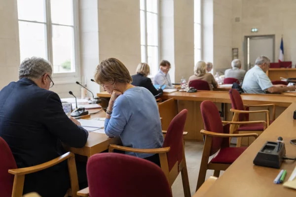 Salle municipale lumineuse avec micros, dossiers et chaise vide, ambiance de résultats du bac