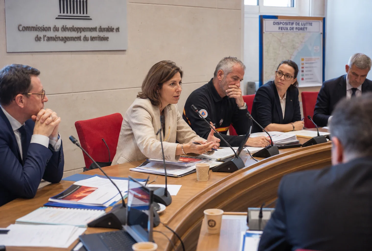 Réunion institutionnelle en France sur les retardants de feu, avec plusieurs experts autour d’une table et des dossiers ouverts.