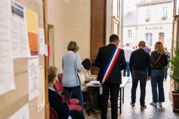 Des citoyens anonymes entrent dans une salle municipale lumineuse pour une réunion politique locale à la mairie.