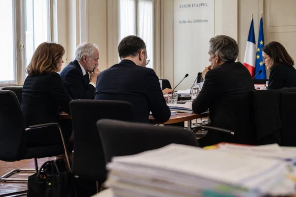 Réunion institutionnelle européenne avec dossiers, micros et silhouettes de dos dans une salle lumineuse et sobre.