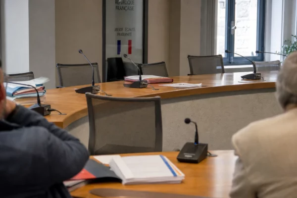 Salle municipale avec chaise vide, micros et dossiers flous, évoquant les enjeux politiques autour de la Coupe du monde 2026.