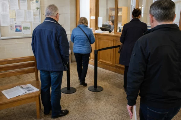 Salle d’accueil municipale lumineuse avec des usagers anonymes, dans une ambiance de vie civique française ordinaire.