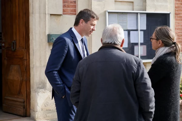 Des habitants discutent devant une mairie de village, dans une scène civique française claire et naturelle.