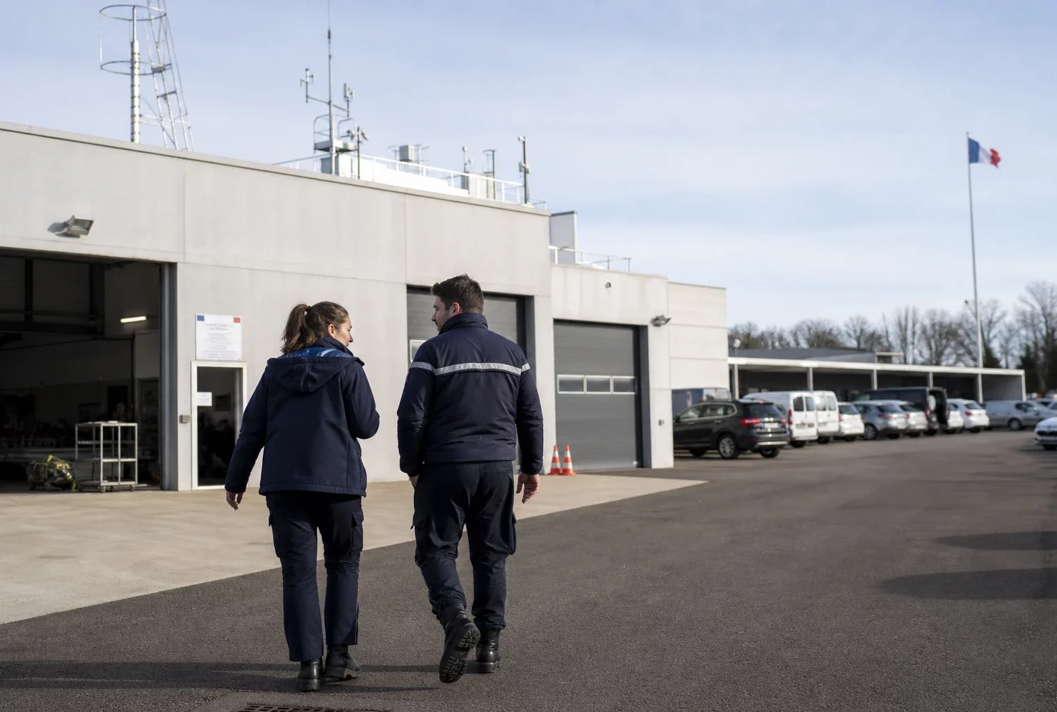 Scène calme dans un site français de sécurité, avec silhouettes anonymes et matériel de terrain en extérieur.