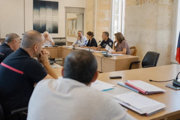 Salle municipale française avec micros, dossiers flous et chaise vide pour évoquer le débat sur la sécurité civile.