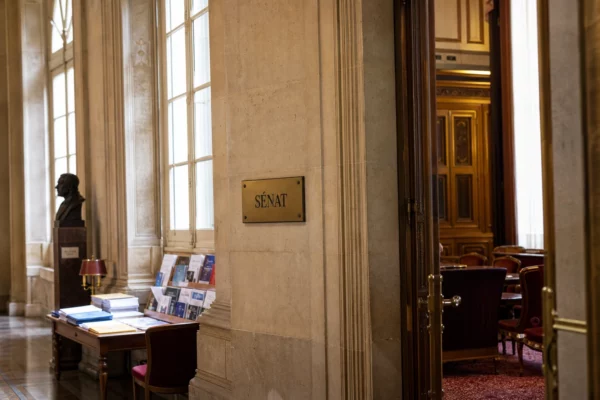 Couloir lumineux du Sénat français avec pierre claire, boiseries et plaque institutionnelle discrète
