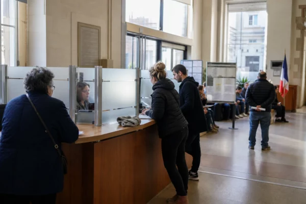 Hall lumineux de service public en France avec usagers anonymes au guichet et ambiance civile calme.