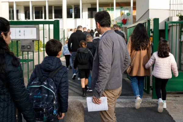 Parents et enfants à l’entrée d’une école publique française, scène de vie citoyenne en lumière naturelle.