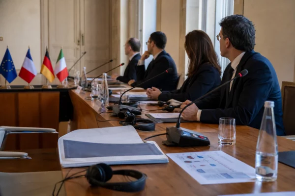 Table de négociation internationale avec dossiers, micros et silhouettes anonymes dans une salle claire