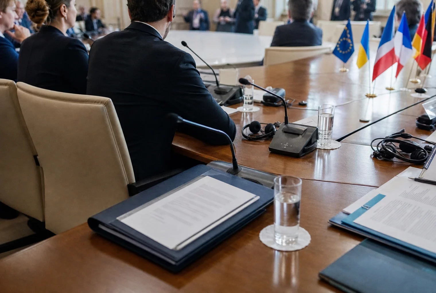 Table de négociation diplomatique à Paris avec dossiers, micros et silhouettes anonymes autour d’un accord européen.