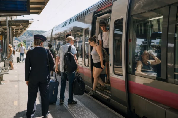 Des voyageurs anonymes montent dans un TER en été sur un quai de gare français, sous une forte chaleur.