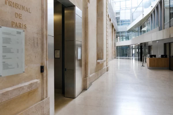 Intérieur vide du tribunal de Paris, architecture institutionnelle claire évoquant une enquête sur une cyberattaque.