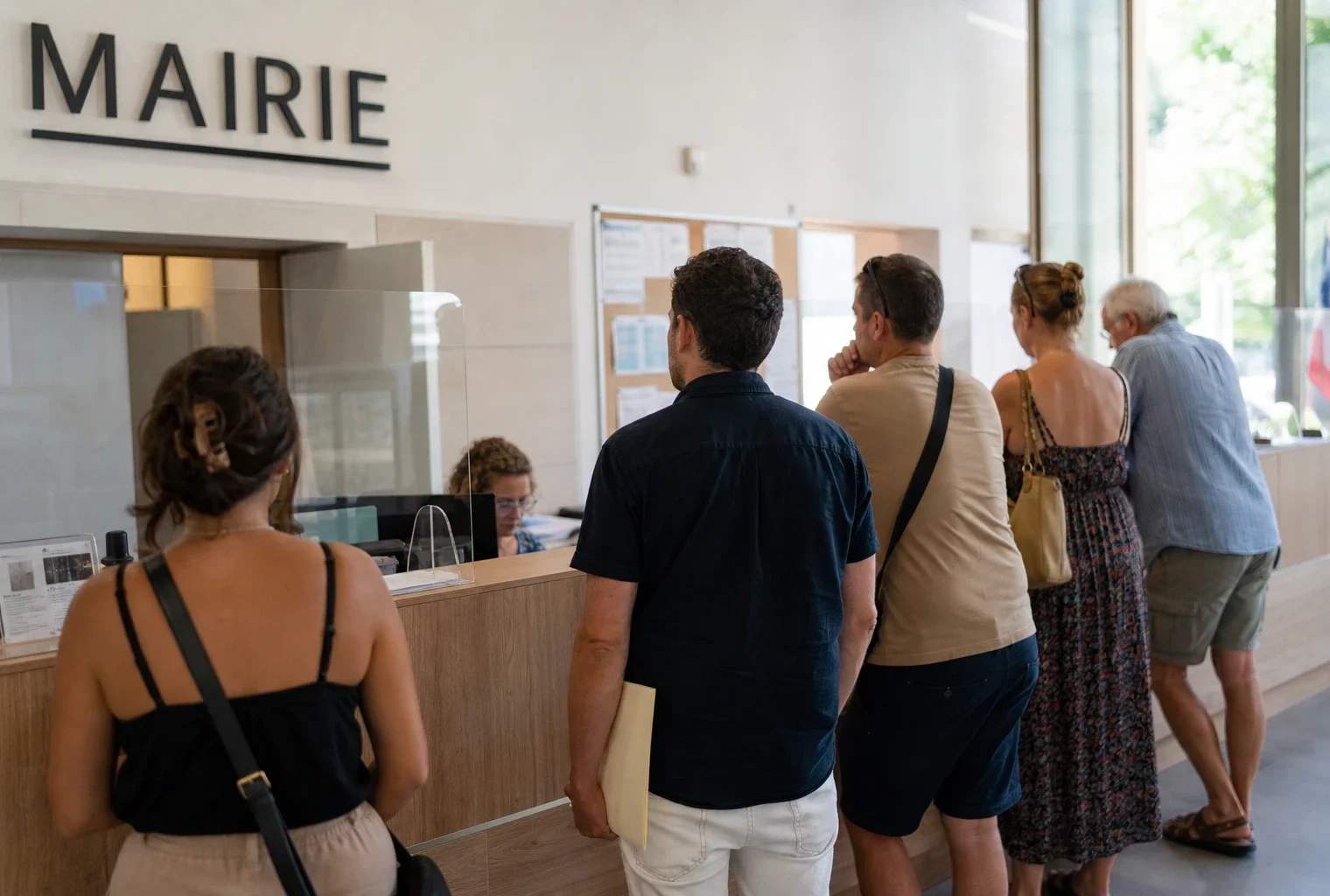Des usagers attendent dans un hall de service public français lumineux pendant un été de forte chaleur.