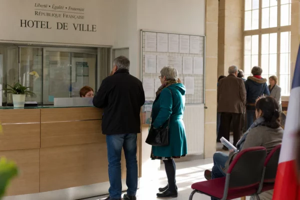 Des citoyens anonymes attendent dans le hall lumineux d’une mairie française, sur fond de vote politique local.