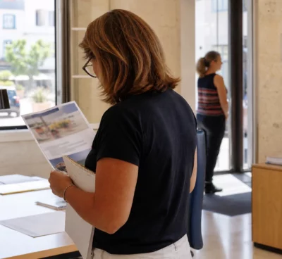 Un agent municipal anonyme consulte un dossier à la mairie d’Agde, dans une lumière naturelle et douce.