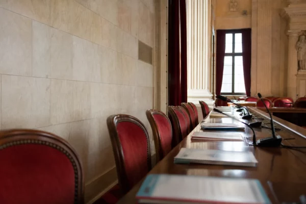 Salle parlementaire française vide avec sièges rouges et micros, évoquant le débat sur l’alliance des écologistes