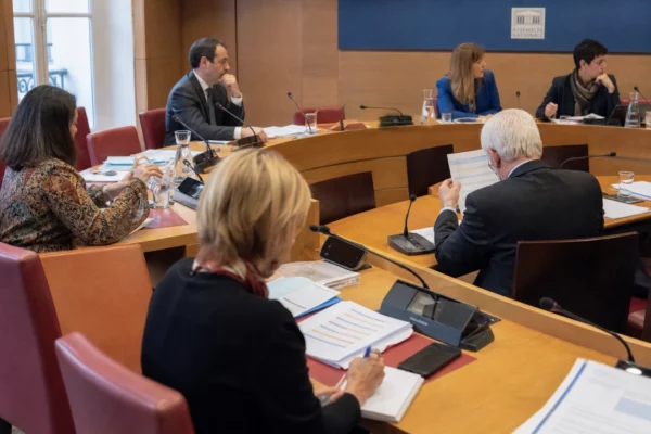 Réunion de commission parlementaire française sur le budget, avec élus anonymes, micros et dossiers sur les tables