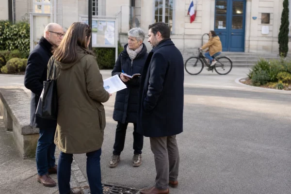 Citoyens anonymes échangeant devant une mairie française lors d’un débat politique local