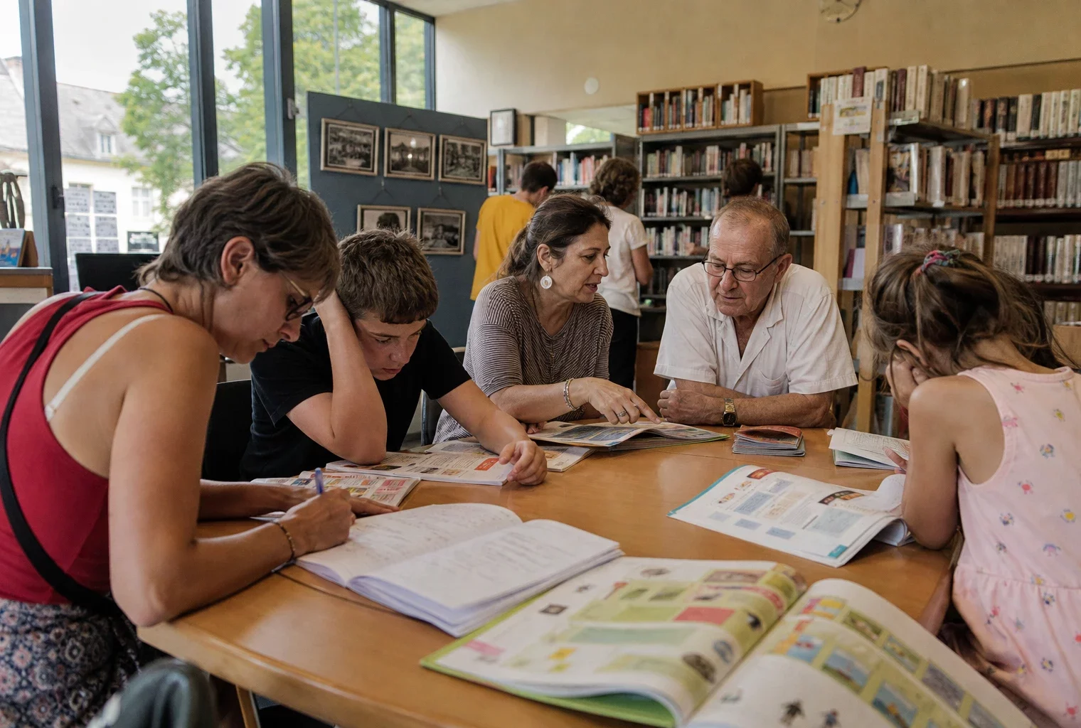 Visiteurs anonymes feuilletant des cahiers de vacances dans une médiathèque municipale française lumineuse
