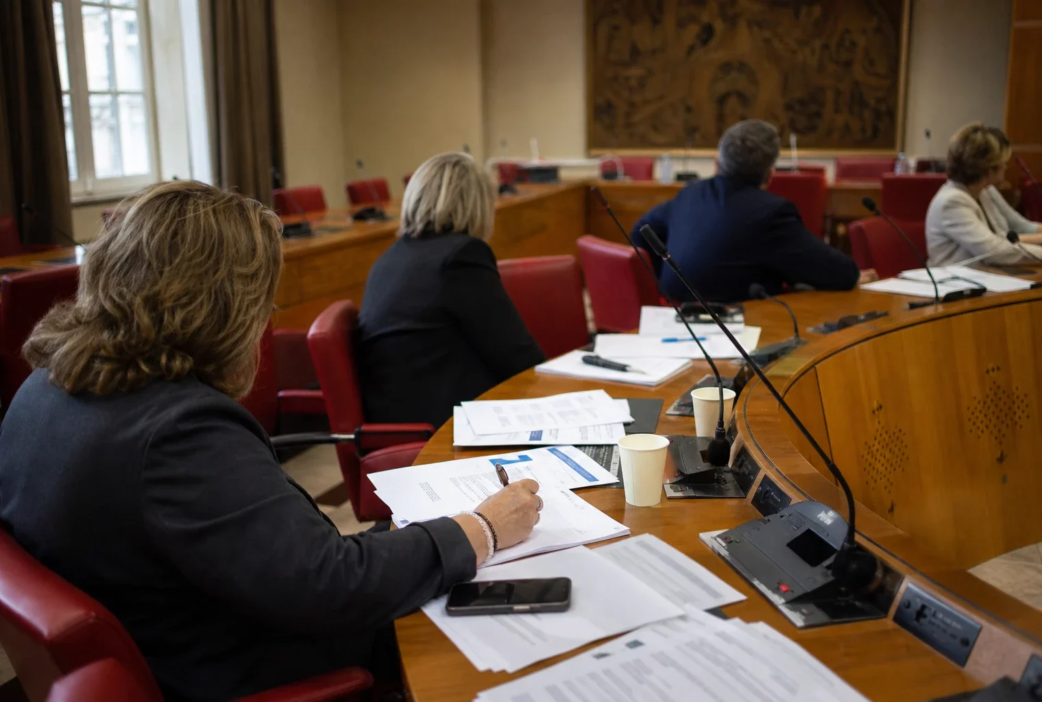 Députés anonymes réunis en commission parlementaire pour examiner le budget 2027, autour de micros et dossiers