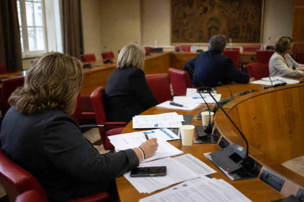 Députés anonymes réunis en commission parlementaire pour examiner le budget 2027, autour de micros et dossiers