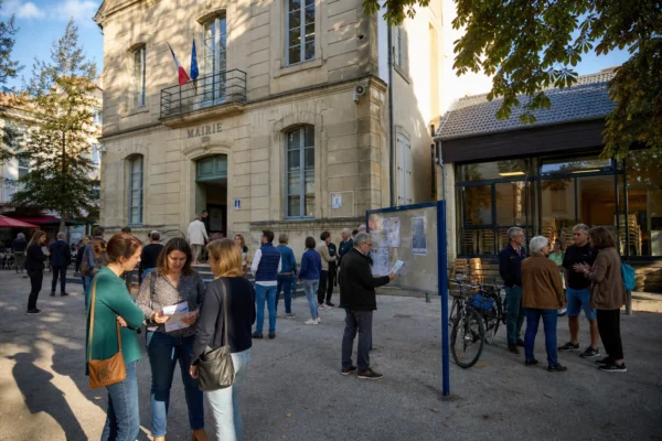 Habitants anonymes échangent sur une place de commune française près d’un lieu civique local