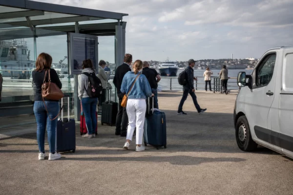 Des voyageurs anonymes attendent dans un terminal maritime français, image de reportage sur les frontières et l’immigration
