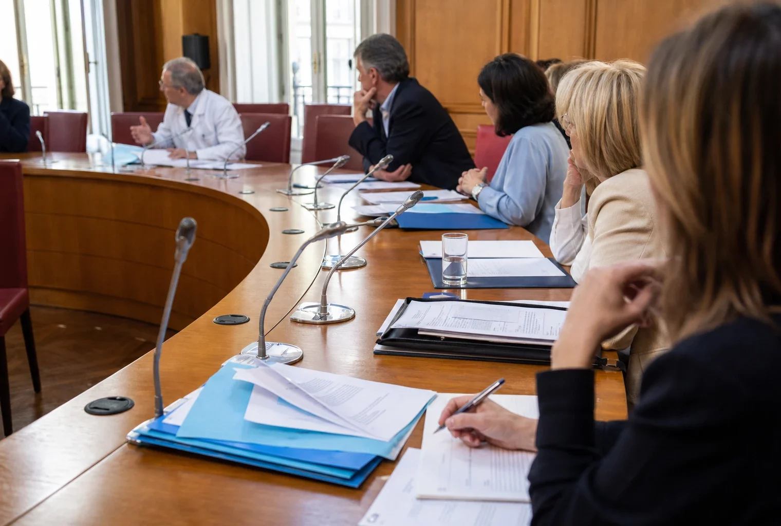 Réunion de commission parlementaire sur l’aide à mourir, avec médecins, dossiers et micros autour d’une table