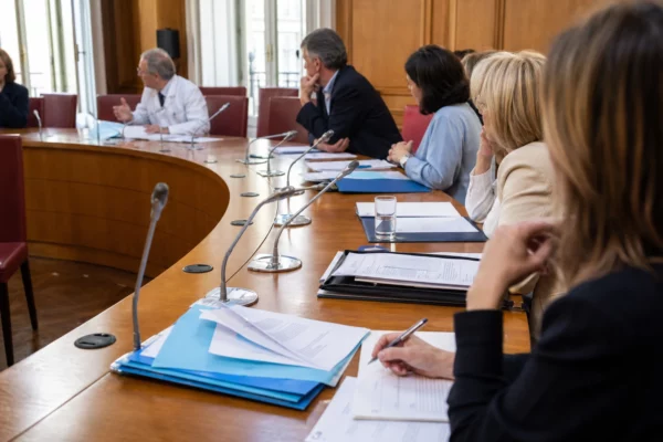 Réunion de commission parlementaire sur l’aide à mourir, avec médecins, dossiers et micros autour d’une table