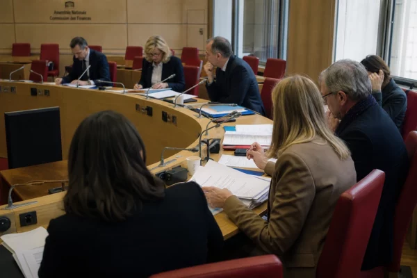 Réunion de commission parlementaire française sur le budget 2027, avec élus anonymes, micros et dossiers sur la table