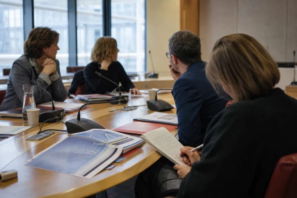 Réunion de commission parlementaire sur l’énergie, avec micros, dossiers et participants anonymes dans une salle claire