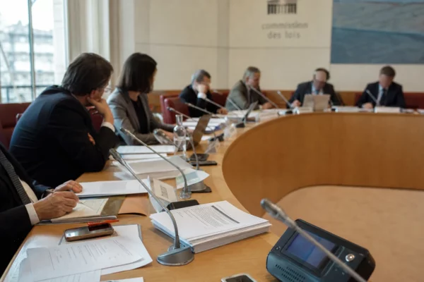 Réunion de commission parlementaire française avec élus anonymes, micros et dossiers autour d’une table