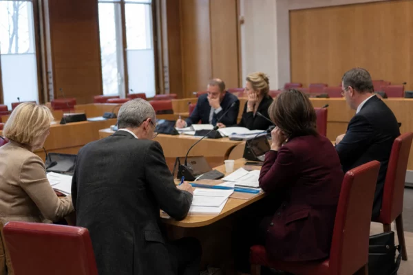 Réunion de commission parlementaire française avec élus anonymes, micros et dossiers autour d’une élection nationale