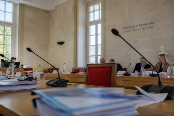 Salle municipale claire avec une chaise vide, micros et dossiers flous lors d’un conseil local en Corse.