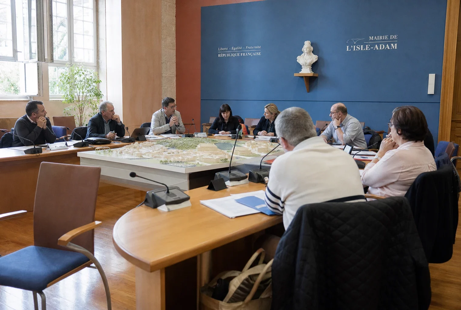 Salle municipale française où des élus examinent un projet de parc de loisirs autour de micros et dossiers flous