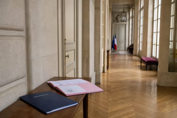 Couloir lumineux d’un bâtiment gouvernemental français avec dossier flou et ambiance institutionnelle calme.