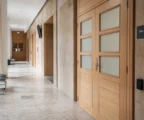 Couloir clair d’un bâtiment public parisien, porte fermée et salle d’audition discrète, ambiance institutionnelle neutre.