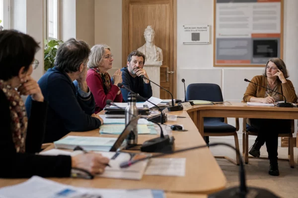 Conseil municipal français sur le climat avec une chaise vide, des micros et des dossiers sur la table