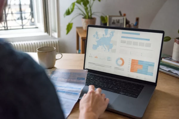 Salarié français consultant une interface économique européenne abstraite sur ordinateur, dans un espace de travail quotidien