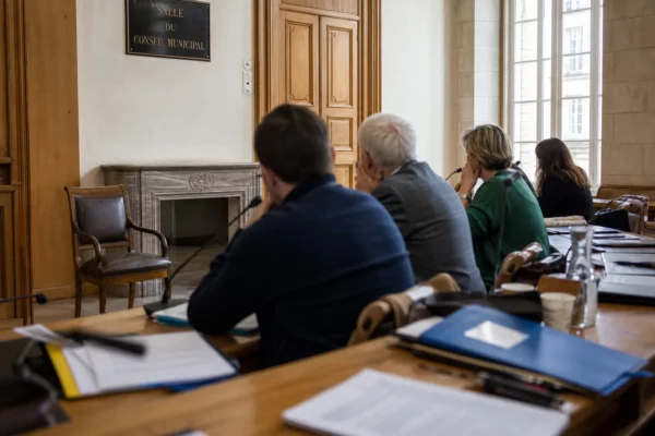 Salle municipale française avec chaise vide, micros et dossiers illustrant le débat stratégique des écologistes pour 2027