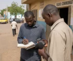 Journalistes d’une radio communautaire au Sahel vérifiant des informations numériques dans une rue ordinaire