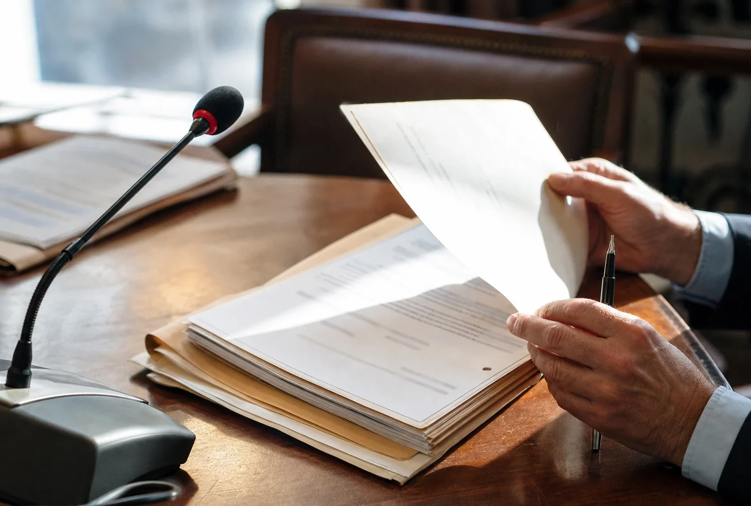 Mains anonymes examinant un dossier de nomination près d’un micro de commission au Sénat