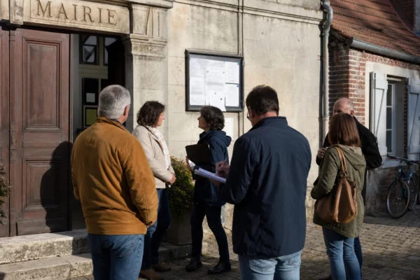 Citoyens anonymes échangeant devant une mairie française lors d’une scène de vie politique locale