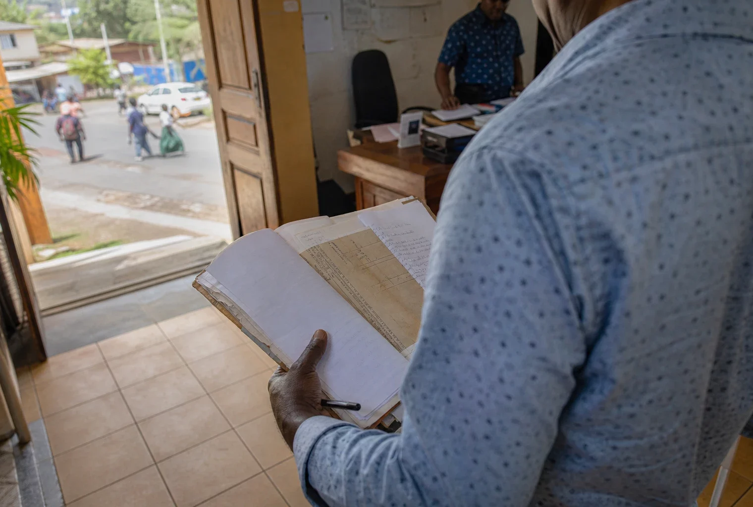 Élu local anonyme consultant un dossier à la mairie de Mayotte, dans une lumière naturelle et un cadre civique réel