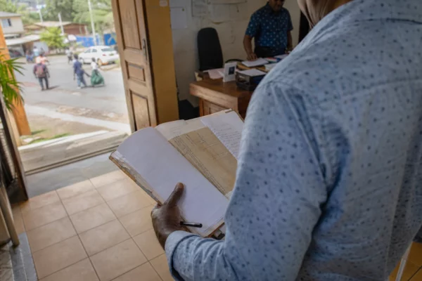 Élu local anonyme consultant un dossier à la mairie de Mayotte, dans une lumière naturelle et un cadre civique réel