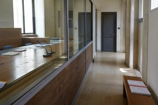 Couloir lumineux d’une institution française menant à une salle d’audition pour une enquête financière