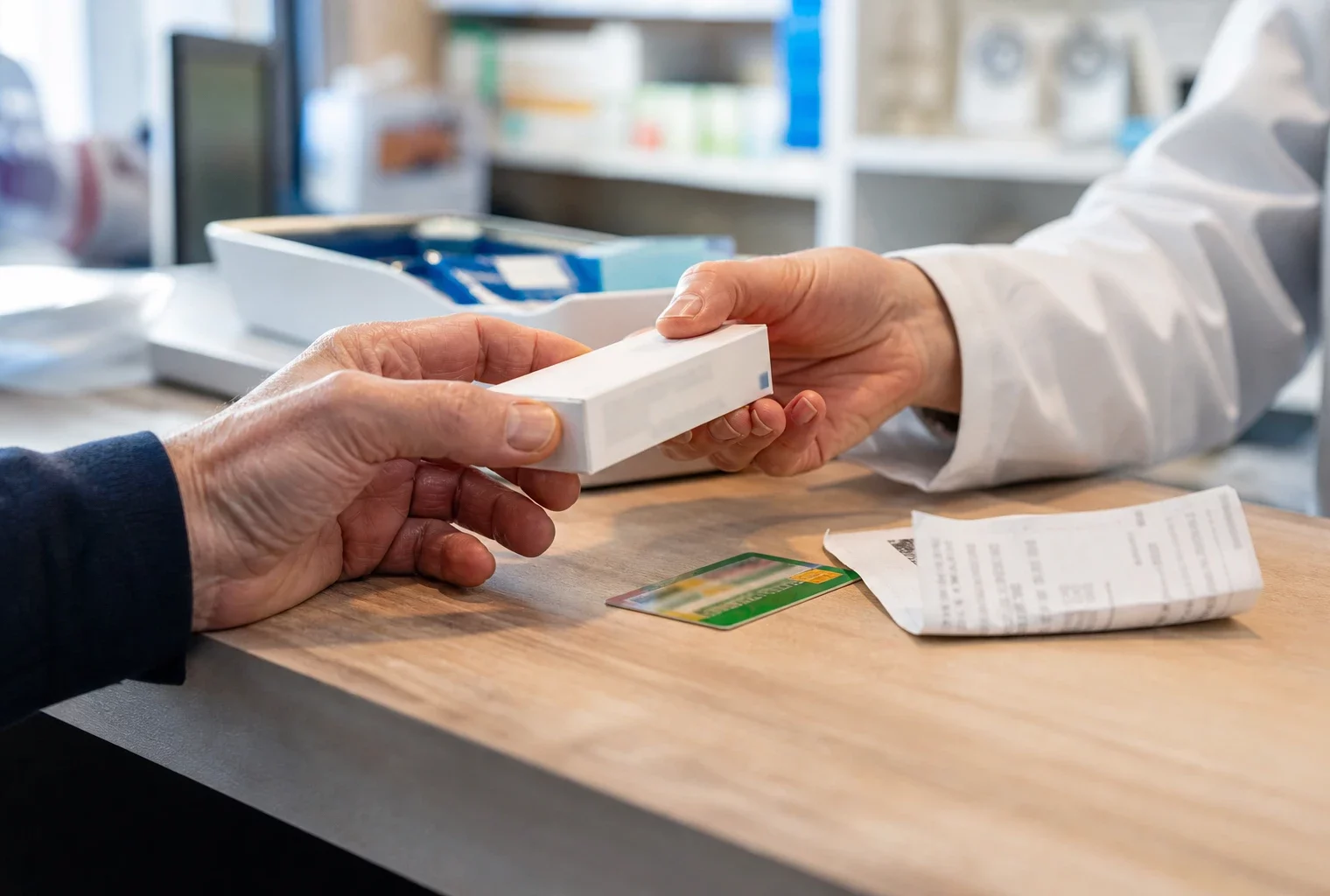 Gros plan sur une main recevant une boîte de médicaments dans une pharmacie française, symbole du reste à charge
