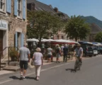 Rue calme d’une petite ville française près de la frontière, avec mairie, marché et habitants anonymes en plein jour.