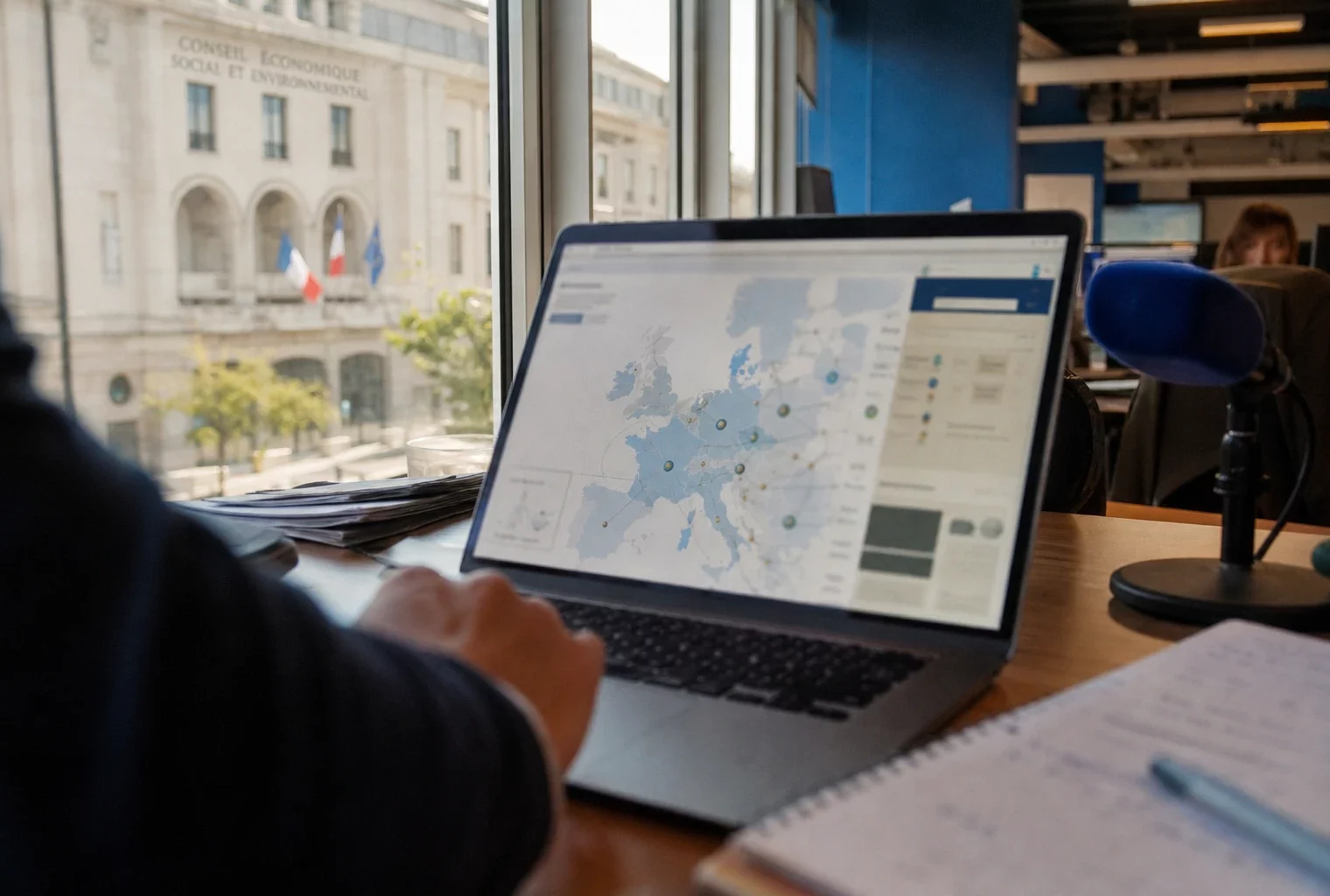 Journaliste consultant une interface européenne abstraite sur ordinateur dans une rédaction française lumineuse
