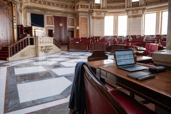 Salle institutionnelle française avec microphones et ordinateur flou, évoquant les ingérences numériques dans le débat démocratique